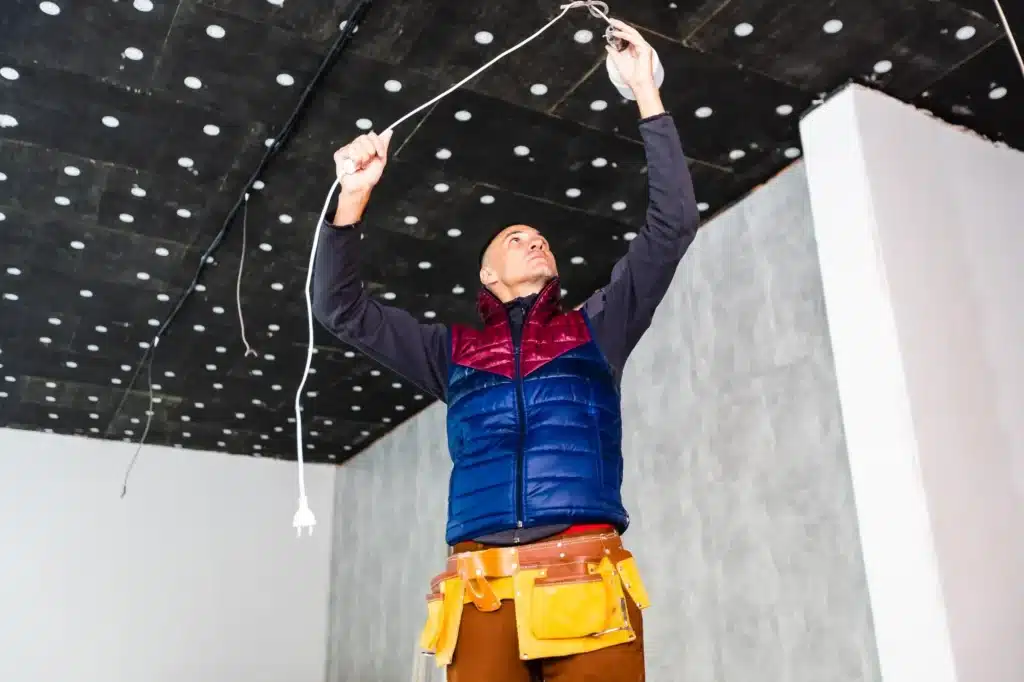 Worker handling electrical wiring at a ceiling